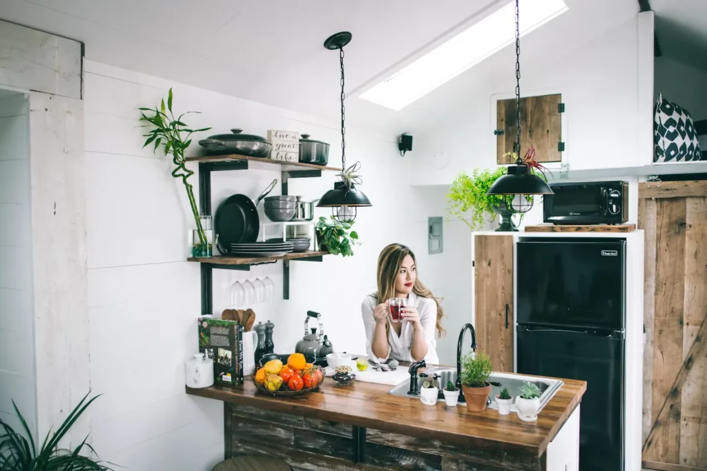 Desain dapur minimalis 2x2, seorang wanita sedang duduk dan menikmati teh di dapur minimalis 2x2